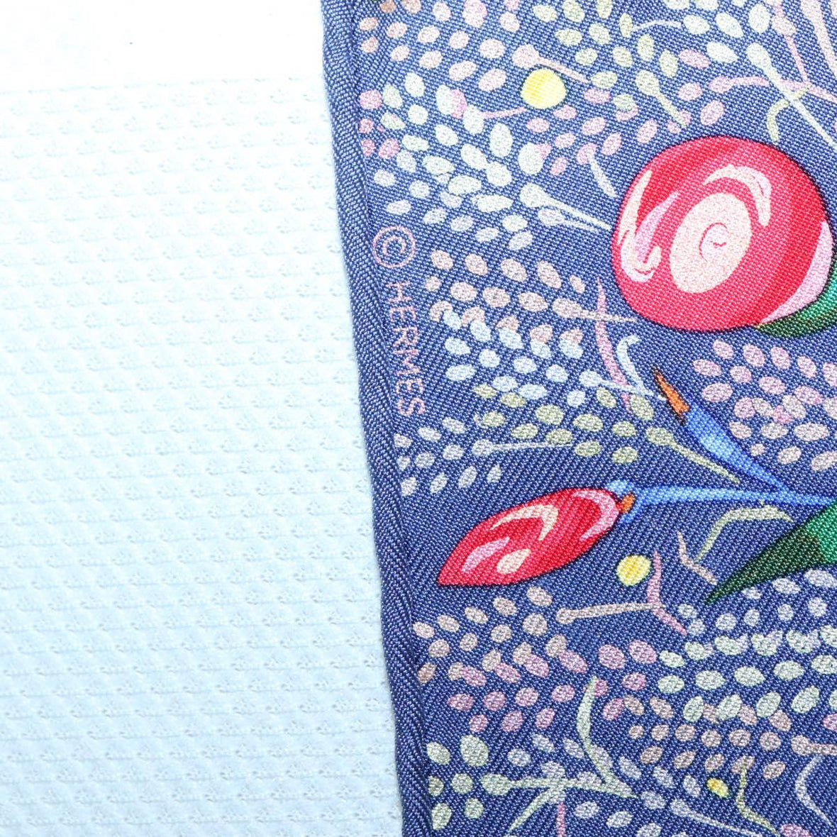 Corner detail of an authentic vintage Hermes silk scarf with floral design, highlighting luxury fashion accessory.