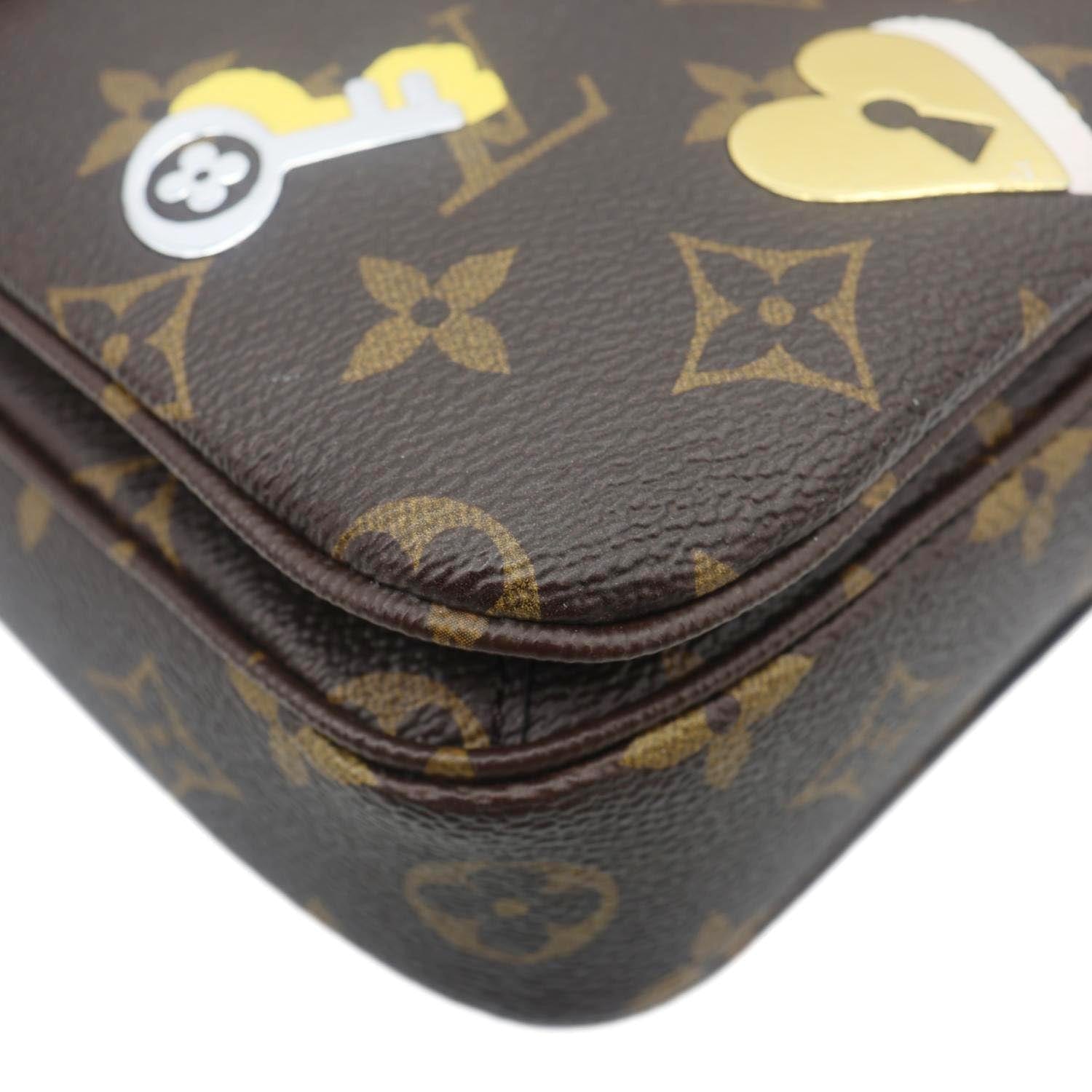 Close-up of LOUIS VUITTON Lovelock Metis Pochette Patches Monogram Canvas Crossbody Bag Brown with key and heart lock patch details.