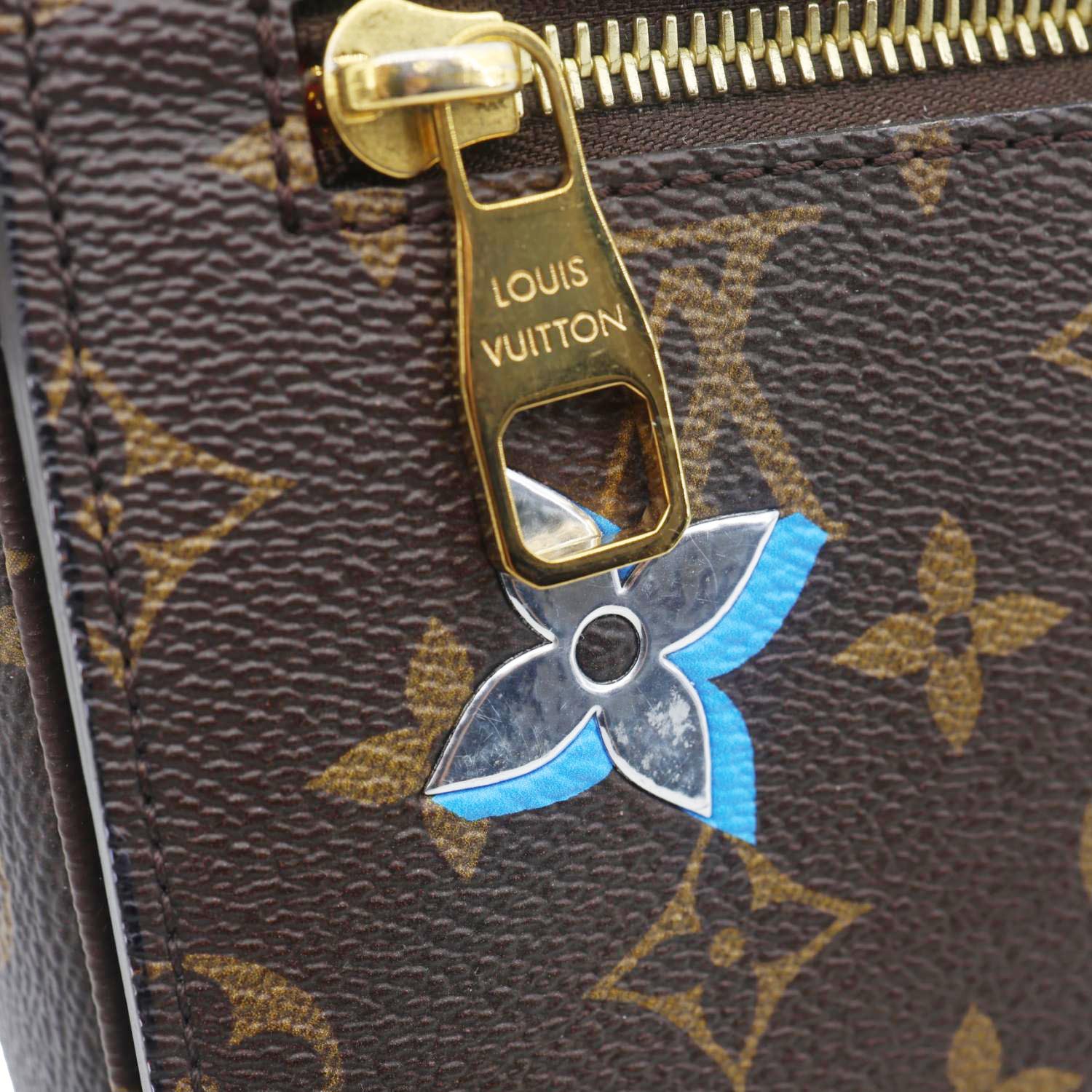 Close-up of LOUIS VUITTON Lovelock Metis Pochette Patches Monogram Canvas Crossbody Bag Brown with zipper detail.