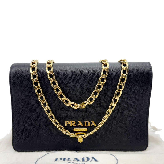 PRADA Saffiano Lux Chain Crossbody Bag Black with gold chain and logo, sleek design, dust bag in background.